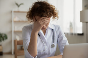 A doctor looks stressed at a laptop